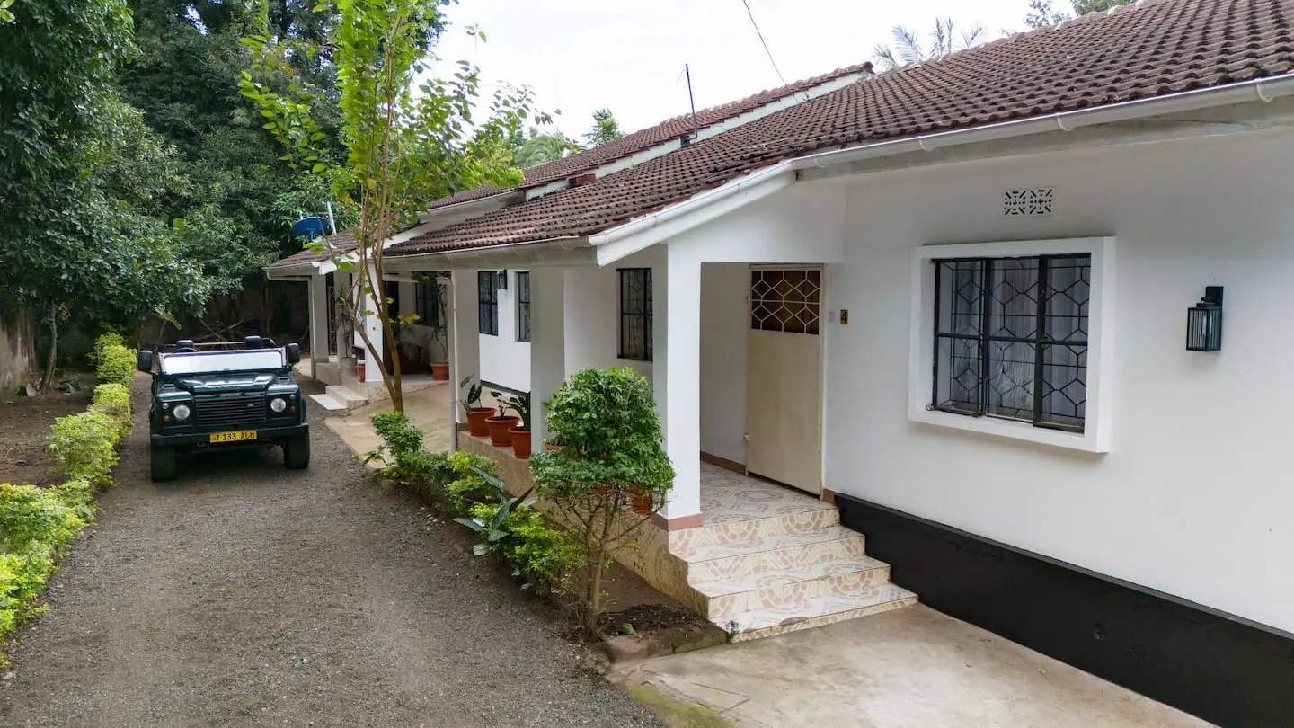 The white house and tiled roof of Home Sweet Hideaway among its green garden in central Arusha
