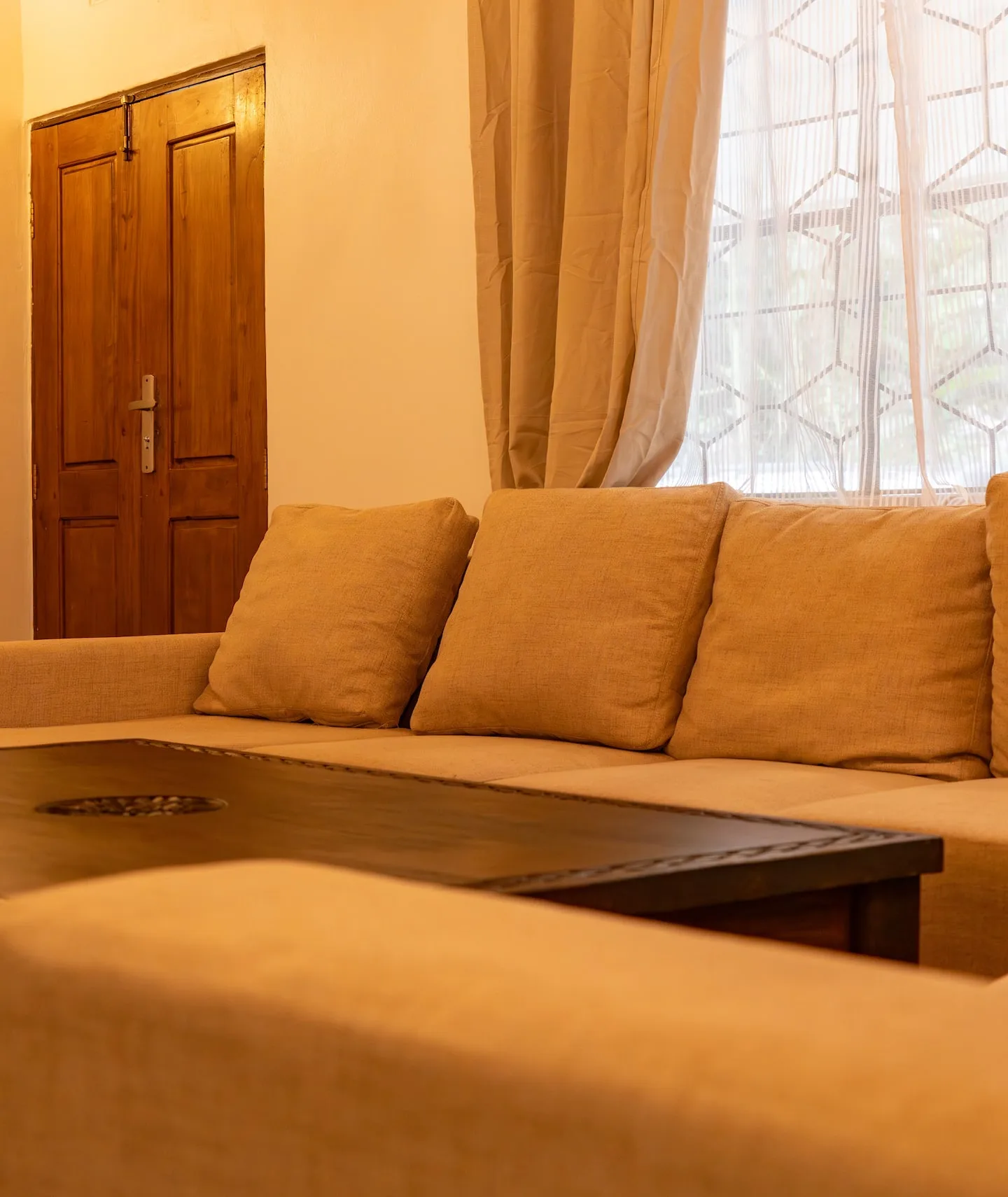 Living room with a wood-beamed ceiling, beige sofas and a smart TV